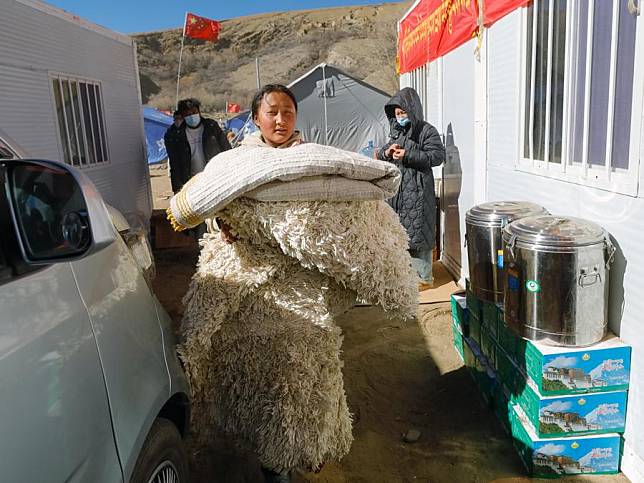 A resident transports supplies from a tent to a mobile house at a temporary resettlement site in Gurum Village in Chamco Township of Dingri County in Xigaze, southwest China's Xizang Autonomous Region, Jan. 10, 2025. (Xinhua/Shen Bohan)