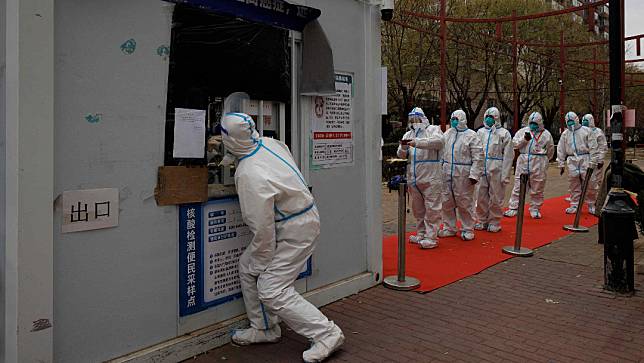 北京穿防護服的疫情封控人員排隊接受核酸檢測。路透社