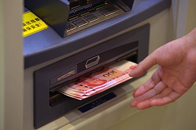 A resident withdraws 100-yuan banknotes from ATM machine at the Beijing Branch of the Bank of Communication in Beijing, capital of China. (Xinhua/Li Xin)