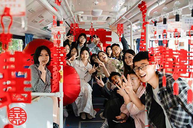 Newlyweds Tang Shanqing and Hu Qiankun pose for a photo with their family members and friends on a wedding bus in Suqian, east China's Jiangsu Province, Oct. 28, 2023. (Xinhua)