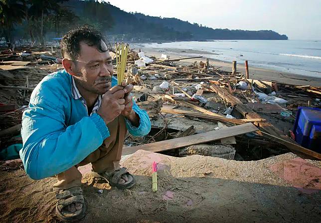 กุศล เวชกุล สวดภาวนาให้ดวงวิญญาณของน้องสาวของเขา ในเช้าตรู่ของวันพุธที่ 29 ธันวาคม 2547 บริเวณชายหาดใกล้เขาหลัก ประเทศไทย น้องสาวของเวชกุลถูกคลื่นซัดหายไปในทะเลและเชื่อว่าเสียชีวิตแล้ว ขณะที่เธอกำลังขายของให้กับนักท่องเที่ยวบนชายหาดยอดนิยมทางเหนือของภูเก็ต (ภาพถ่ายโดย AP Photo/David Longstreath)