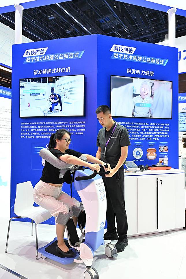 A participant (L) tries an auxiliary device for elder people at the exhibition area of the 2024 China Internet Conference in Beijing, capital of China, July 9, 2024. (Xinhua/Li Xin)