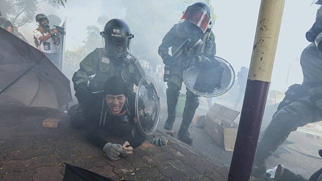 Riot police are seen making an arrest amidst tear gas outside of the Chinese University of Hong Kong.