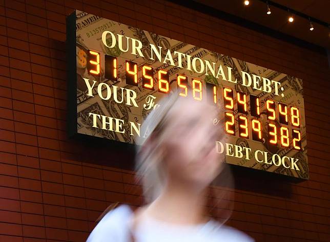 A woman walks past the National Debt Clock in New York, the United States, on June 1, 2023. (Xinhua/Li Rui)