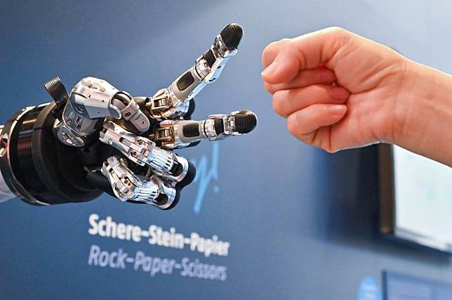A visitor plays rock paper scissors with an intelligent robot at Hannover Messe in Hannover, Germany, on April 23, 2024. (Xinhua/Ren Pengfei)