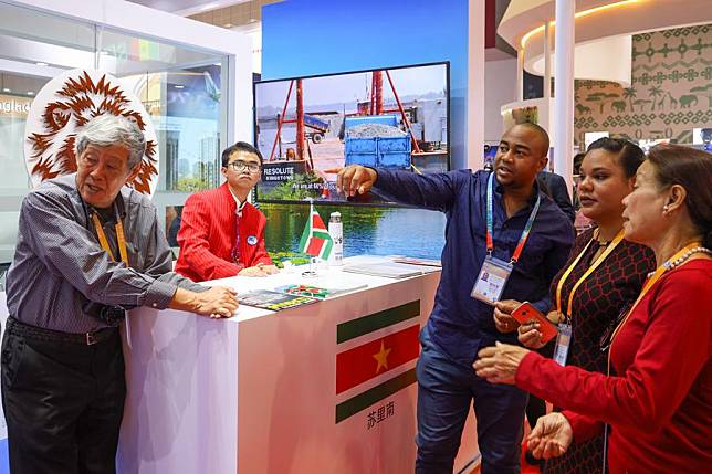 A staff member (3rd R) introduces Suriname to visitors at the first China International Import Expo (CIIE) in Shanghai, east China, Nov. 6, 2018. (Xinhua/Liu Dawei)
