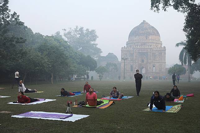 印度民眾不畏眼前霧霾的威脅，在慘灰的露天公園草地上鋪滿地墊，全身心專注在提升身心靈的瑜珈運動上。 路透社 / 達志影像