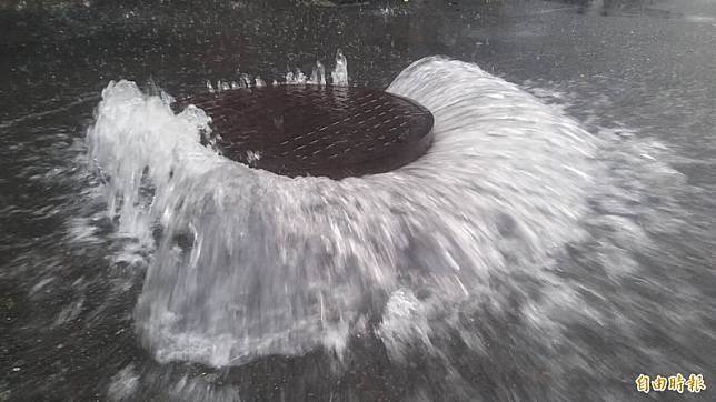 高雄地區發布大雷雨警示又遇愛河漲潮，鹽埕多處積水連人孔蓋都漂浮。(記者黃良傑攝)