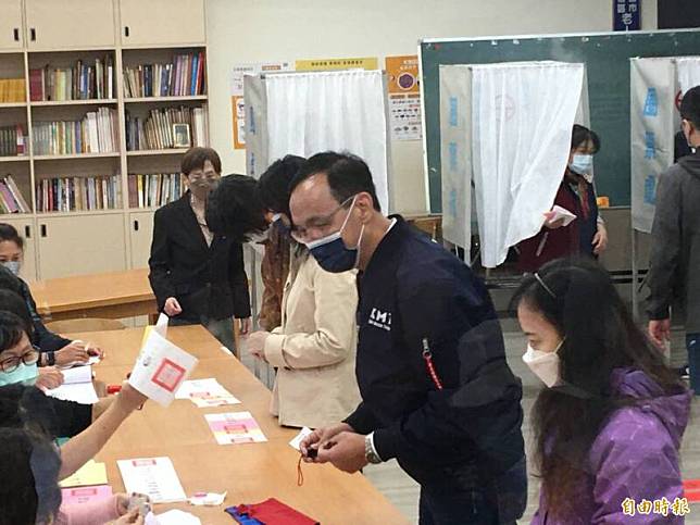 國民黨主席朱立倫(中)今早前往桃園市八德大智里投開票所投票，當時他身穿有國民黨英文簡寫「KMT」的外套，被質疑可能違反選罷法。(記者謝武雄攝)