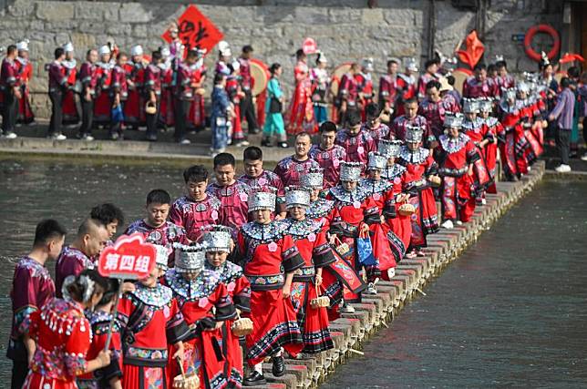 The newlyweds dressed in wedding costumes parade in Fenghuang ancient town in Xiangxi Tujia and Miao Autonomous Prefecture, central China's Hunan Province, Nov. 11, 2024. A hundred couples from all over China attended a mass wedding ceremony at Fenghuang ancient town. (Photo by Guo Liliang/Xinhua)