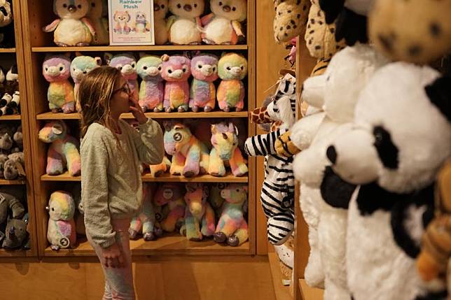 A girl visits a gift shop with giant panda-themed plushies at the San Diego Zoo in San Diego, California, the United States, on Feb. 22, 2024. (Photo by Zeng Hui/Xinhua)
