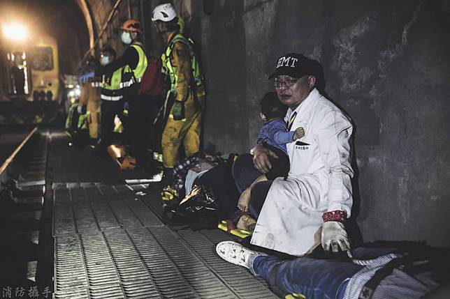 吳坤佶在救難現場，曾抱著一個倖存的孩子，蹲坐在路邊，被消防攝手蔡哲文拍下，畫面讓人看了相當動容。(消防攝手蔡哲文提供)