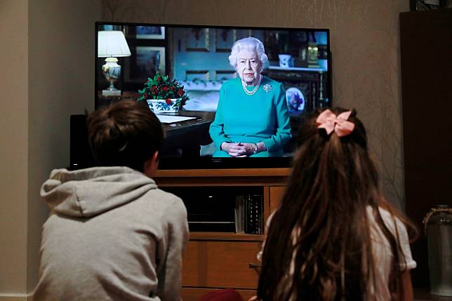 Two children watch Britain's Queen Elizabeth during a televised address to the nation at their home in Hertford, Britain. Photo: Reuters