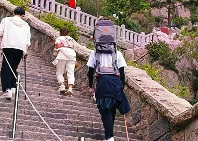 陪爬員綁上背娃神器，帶客人的年幼女兒上山。