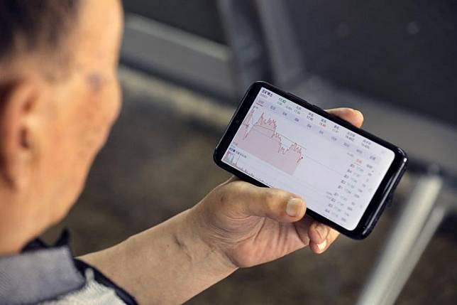 A Chinese investor uses a mobile phone to check stock prices at a securities brokerage house in Beijing. Photo: EPA-EFE