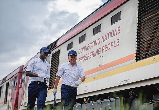 Chinese instructor Jiang Liping &reg; and apprentice Horace Owiti walk past a train carriage on the Mombasa-Nairobi Standard Gauge Railway in Nairobi, Kenya, May 23, 2023. (Xinhua/Wang Guansen)