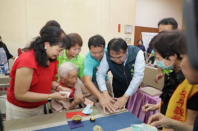 黃偉哲市長與長輩們把玩陶土手印板，祝福長輩們健康長壽，「千歲宴」活動充滿喜氣與溫馨感。（圖：南市府提供）