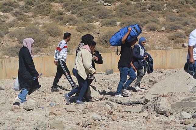 Displaced people from Lebanon cross a destroyed road caused by an Israeli airstrike near the Masnaa Border Crossing, Lebanon, Oct. 4, 2024. (Photo by Taher Abu Hamdan/Xinhua)