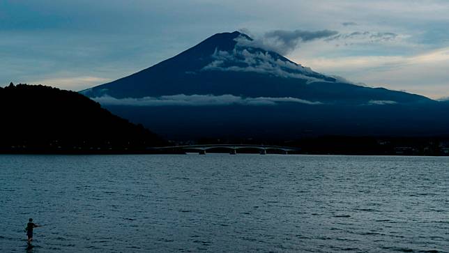 日本富士山，圖為1名男子在日本山梨縣河口湖的水中釣魚。美聯社