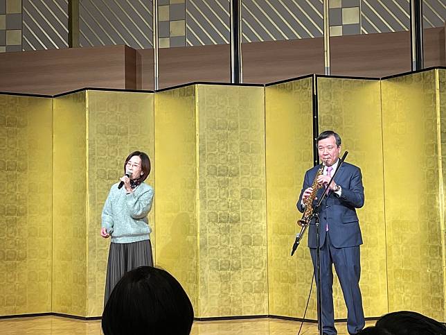 台北駐日經濟文化代表處24日晚間舉辦忘年會，席間駐日大使李逸洋演奏薩克斯風、並在夫人的歌聲下，一起「雙劍合璧」合演經典台語名曲《深情海岸》。（鄭仲嵐 攝）