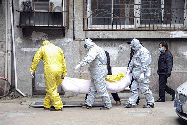 Funeral home workers remove the body of a person suspect to have died from a virus outbreak from a residential building in Wuhan in early February. Photo: AP