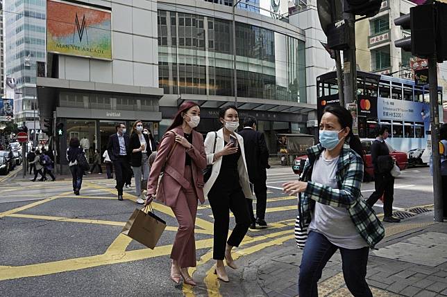 People wearing masks, walk across a street in Hong Kong on February 24. The coronavirus outbreak has struck fears in the market as property sales came to near a standstill. Photo: AP Photo