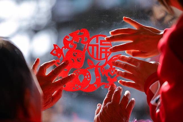 An elder and a staff member of a rest home paste a paper-cutting on a window to greet the upcoming Chinese Lunar New Year in Qingdao, east China's Shandong Province, Jan. 24, 2025. (Photo by Zhang Ying/Xinhua)