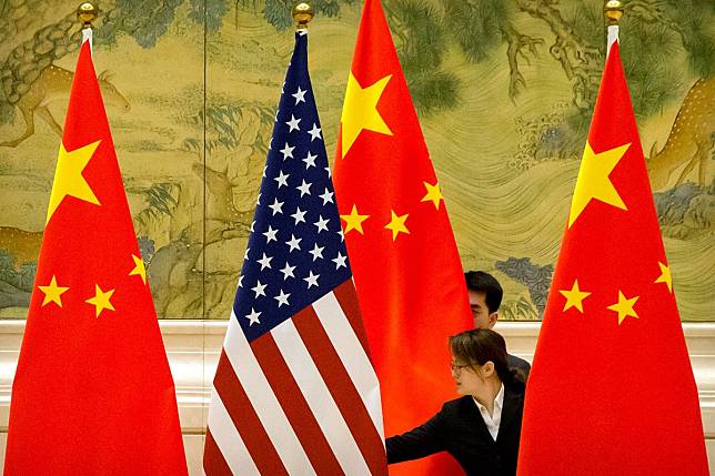 Chinese staff members adjust US and Chinese flags before the start of trade talks at the Diaoyutai State Guesthouse in Beijing in February. Photo: Reuters