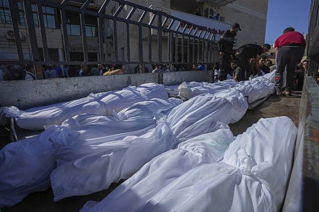 2023 年 10 月 15 日星期日，加薩走廊中部代爾巴拉赫阿克薩醫院外，在空襲中喪生的以色列屍體被蓋好床單後裝上卡車。（AP）