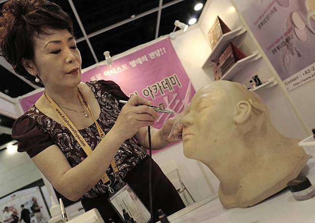 殯葬業者模擬示範以噴槍化妝術，為死者上妝。（美聯社）
