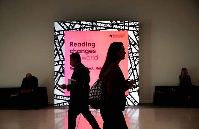 People walk past a light box poster at the 76th Frankfurt Book Fair in Frankfurt, Germany, Oct. 16, 2024. (Xinhua/Zhang Fan)