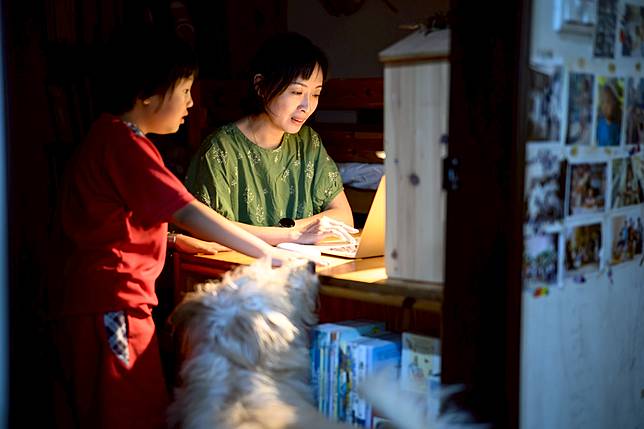 諶淑婷在工作與孩子間尋求平衡，一邊居家工作一邊回應孩子需求。在缺乏經濟資本外包勞務的情況下，面對育兒與長照的重疊壓力，「離開職場」可能成為中產世代在時間貧窮下的無聲選擇。（攝影／黃世澤）