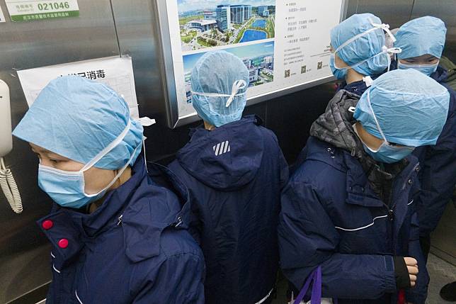 Workers on a lift at the Tongji Hospital in Wuhan, China, faced in different directions to prevent cross infection. Photo: Xinhua