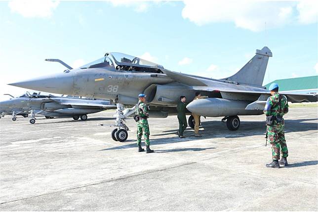  法軍「飆風」戰機因天氣因素被迫轉降印尼機場。圖為法軍人員在印尼警衛士兵戒護下，為轉降戰機實施檢查。（取自推特）