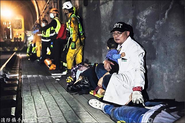 吳坤佶抱著倖存的男童，蹲坐在隧道邊安撫他。(消防攝手蔡哲文提供)
