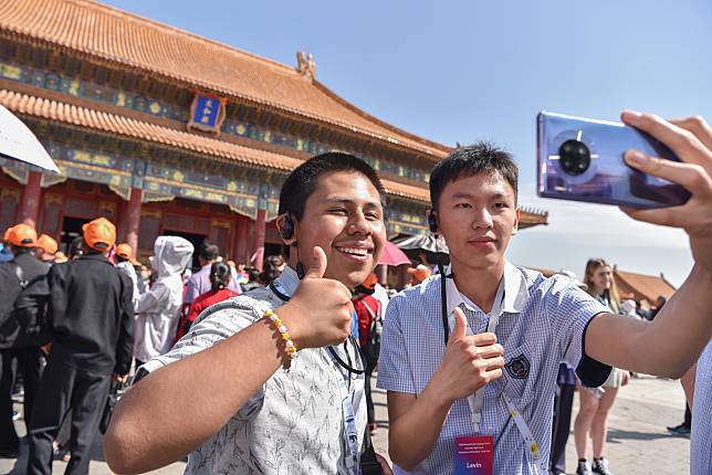 A student (L) of the Muscatine High School delegation takes selfies at the Palace Museum in Beijing, capital of China, April 18, 2024. (Photo by Liu Zunshuan/Xinhua)