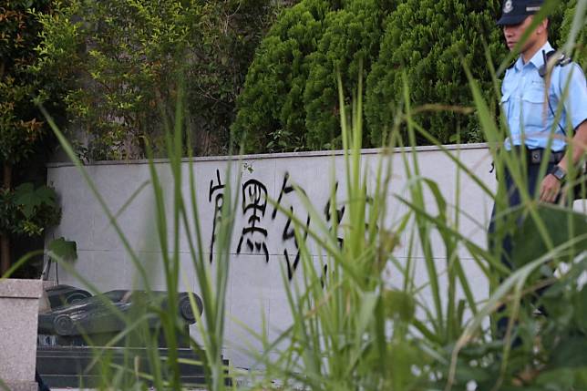 A police officer stands guard at the graves of Junius Ho’s parents, after vandals struck. Photo: Sam Tsang