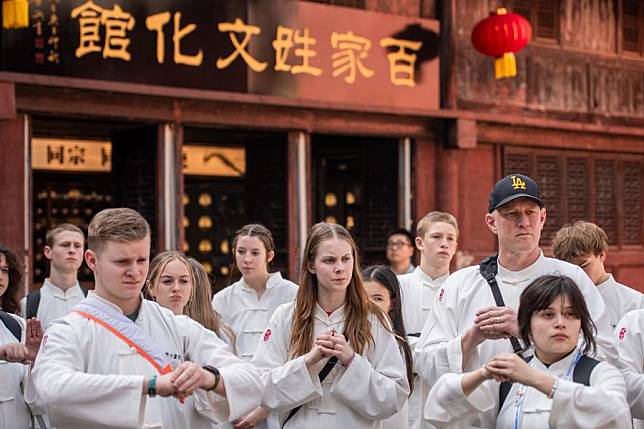 Members of a delegation of high school students from the U.S. state of Washington learn traditional “fist and palm” salute on Wudang Mountain, a sanctuary for the Taoism martial art, in central China's Hubei Province, March 22, 2024. (Xinhua/Wu Zhizun)