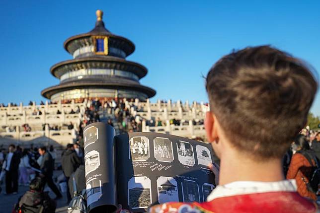 Evan Kail holds a copy of his donated photo album as he visits Tiantan (Temple of Heaven) Park in Beijing, capital of China, Nov. 21, 2024. (Xinhua/Ju Huanzong)