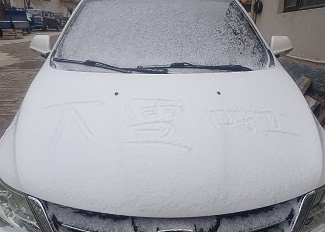 北京路邊車輛覆上一層薄雪。