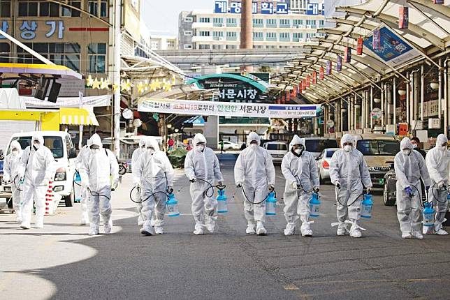 韓國疫情近日擴大，確診數甚至單日以百例暴增，防護人員正在大街執行消毒作業。（達志影像）