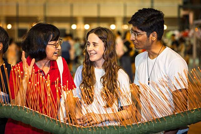 The photo taken on Sept. 7, 2024 shows a tourism volunteer translating for foreigners participating in the Tai Hang Fire Dragon Dance, in Hong Kong, south China. (Hong Kong Tourism Board/Handout via Xinhua)