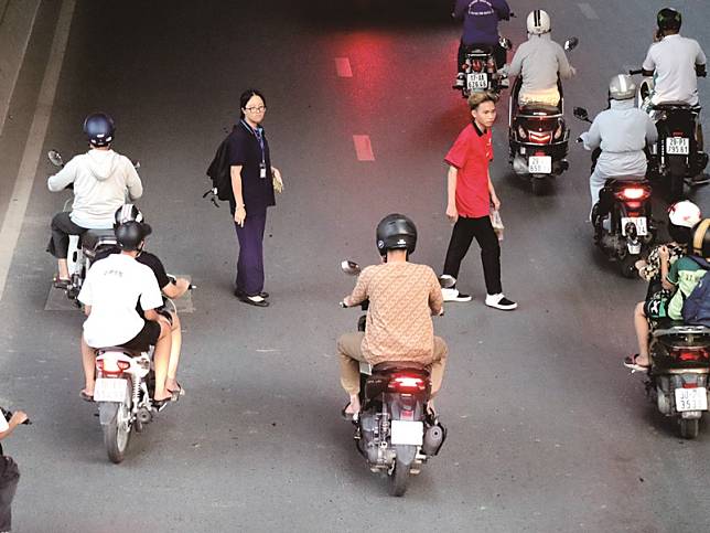 在越南過馬路是一大挑戰，汽機車、行人互不相讓，行人必須懂鑽、敢拚，將近身不到一公尺的機車與汽車視為無物，才能成功過馬路。