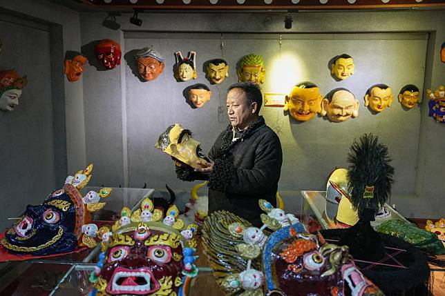 Shilok looks at a traditional Tibetan mask at an exhibition hall of a cooperative in Dagze District of Lhasa, southwest China's Xizang Autonomous Region, Dec. 9, 2024. (Xinhua/Ding Ting)