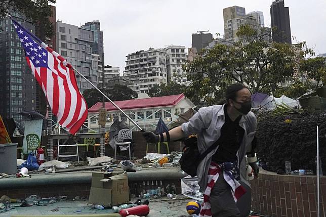 A protester holds an American flag on Wednesday at the Hong Kong Polytechnic University, where anti-government protesters remain under police siege. Photo: AP